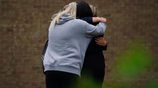 People hugging by the gates of Tewkesbury Academy in Gloucesershire, which was in lock down after a teenage boy was arrested following reports a pupil stabbed a teacher. Picture date: Mo<em></em>nday July 10, 2023.

