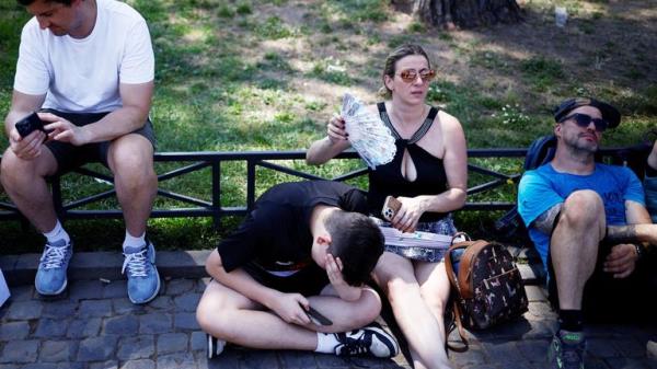 People sit in the shade near the Colosseum to shelter from the sun during a heatwave across Italy, in Rome, Italy July 11, 2023. REUTERS/Guglielmo Mangiapne