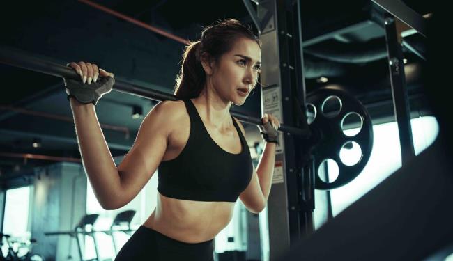 Sporty woman exercising with weight plate in the gym.