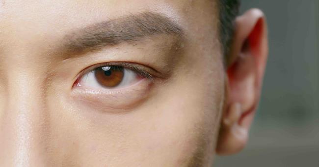 slow motion of male eye close up from asian young man half face