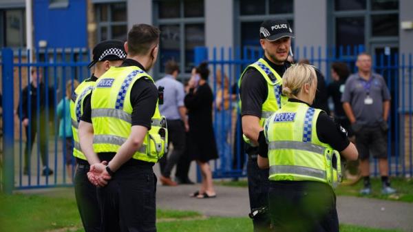 Police Officers at the gates of Tewkesbury Academy in Gloucesershire, which was in lock down after a teenage boy was arrested following reports a pupil stabbed a teacher.  Picture date: Mo<em></em>nday July 10, 2023. PA Photo. Teachers at the nearby Tirlebrook Primary School posted a message on Facebook saying its school had also been locked down on police advice and urged parents not to come to the school. See PA story POLICE Tewkesbury. Photo credit should read: Ben Birchall/PA Wire