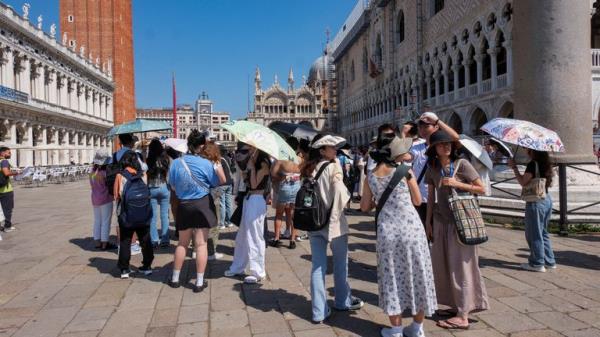 FILE PHOTO: Tourists shelter from the sun in St. Mark&#39;s Square as the city gears up for &#39;Redentore&#39; festival celebrations in Venice, Italy, July 15, 2023. REUTERS/Manuel Silvestri/File Photo
