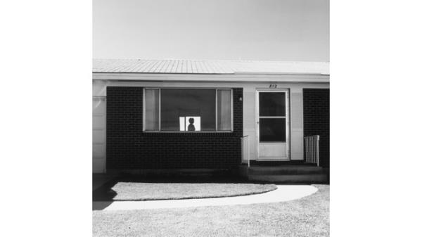 Silhouette of person visible through suburban house window