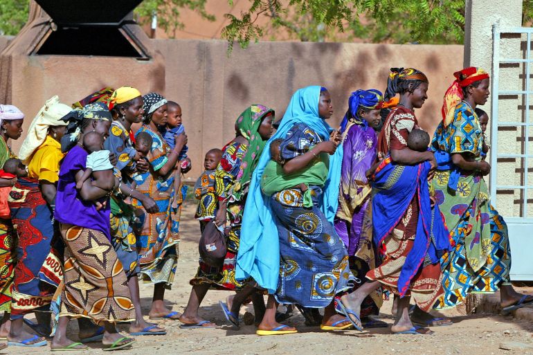 Rural women with their children rush into an emergency feeding center in the town of Guidan Roumdji, southern Niger