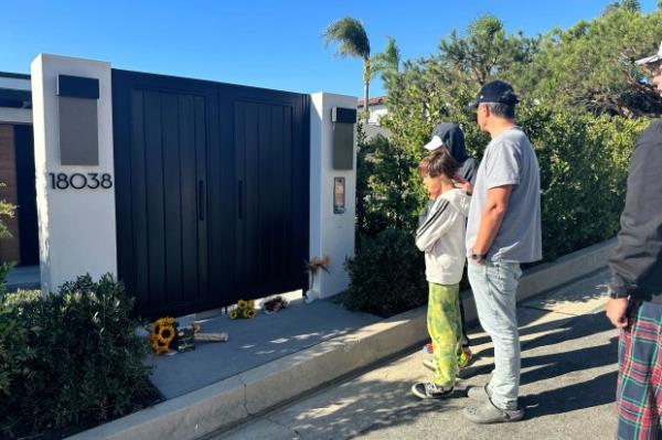 Mourners stand outside the home of actor Matthew Perry, Sunday, Oct. 29, 2023, in the Pacific Palisades area of Los Angeles. Perry, who starred as Chandler Bing in the hit series "Friends," has died. He was 54. (AP Photo/Eugene Garcia)