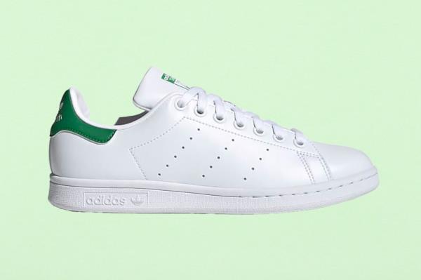 White and green Adidas tennis shoe on a fresh green paper texture background