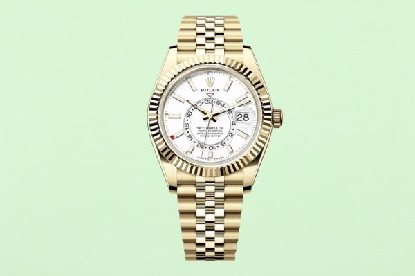 Gold watch with a white face on a fresh green paper texture background