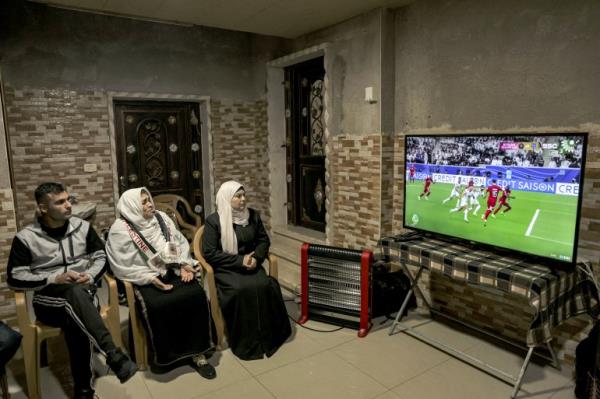 The grandmother (2nd-L) of Palestine's defender and captain #07 Musab al-Battat prays as she watches the live television broadcast of the Qatar 2023 AFC Asian Cup football match between Qatar and Palestine, at their family home in the village of al-Dhahiriya south of Hebron in the occupied West Bank on January 29, 2024. (Photo by HAZEM BADER / AFP)