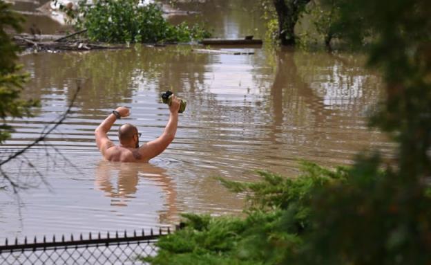 A man wades through floodwaters.