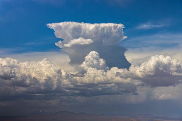 Giant cumulo<em></em>nimbus cloud rising over lower clouds.