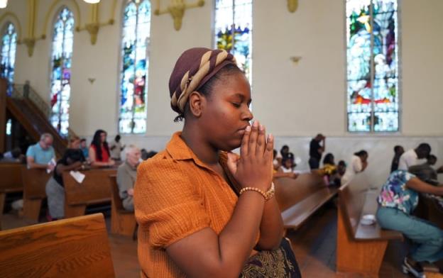 A woman prays while kneeling in a church.