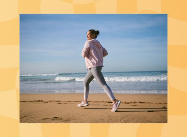 fit, happy middle-aged brunette woman in leggings and pink jacket running on the beach