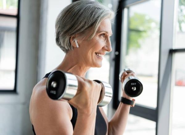 happy woman lifting weights, co<em></em>ncept of how many days a week to exercise for results