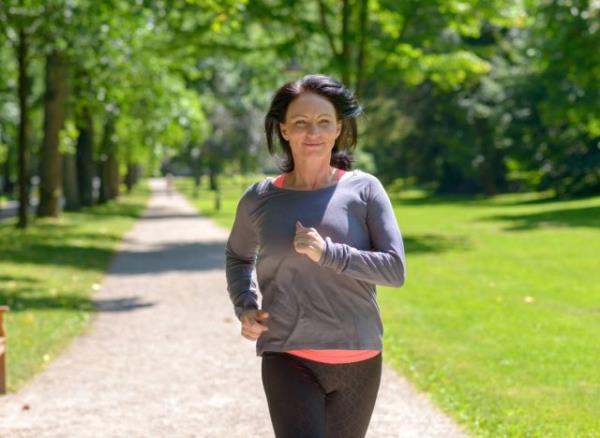 middle-aged woman running outdoors, co<em></em>ncept of how often to do cardio to lose belly fat