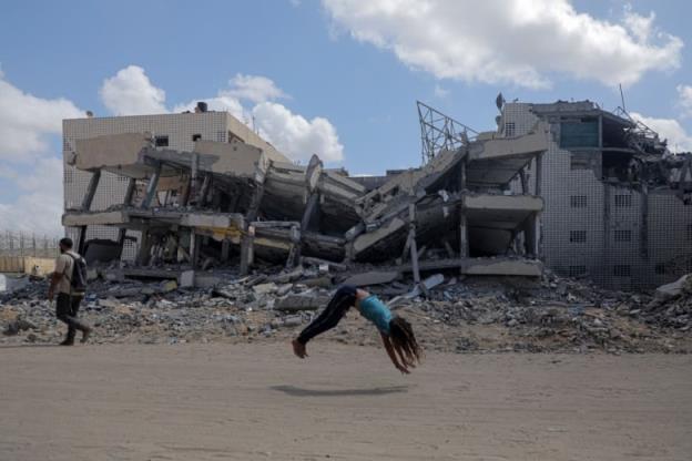 A boy does a bridge on top of a collapsed building.