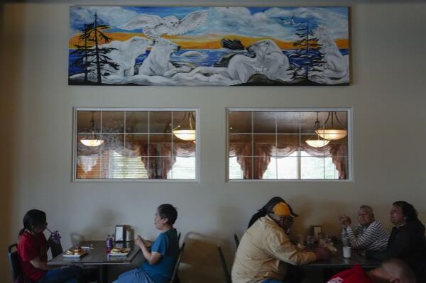 Patrons eat lunch below a mural depicting polar bears and other wildlife, Monday, Aug. 5, 2024, at the Seaport Hotel in Churchill, Manitoba. (AP Photo/Joshua A. Bickel)