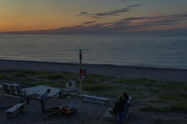 People start a bo<em></em>nfire at sunset next to a sign warning them of polar bears, Saturday, Aug. 3, 2024, in Churchill, Manitoba. (AP Photo/Joshua A. Bickel)