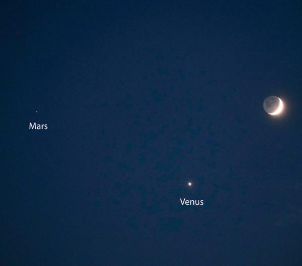 Black sky with big crescent moon at right, small bright dot of Venus at bottom and even smaller Mars at left.