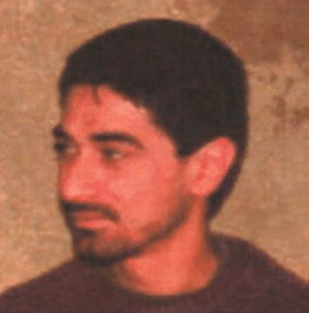 A wanted poster is is shown depicting a dark haired man with a mustache and thin beard.