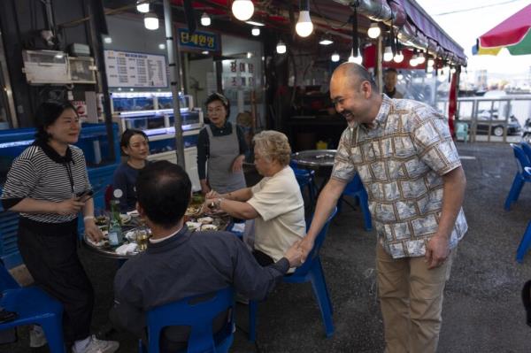 Kenneth Barthel, right, who was adopted to the United States at 6 years old, talks with diners in the neighborhood wher<em></em>e he remembers being abando<em></em>ned by his mother, in Busan, South Korea, Friday, May 17, 2024. Barthel was posting flyers in the area featuring his photos in the hopes of finding his birth family. (AP Photo/Jae C. Hong)