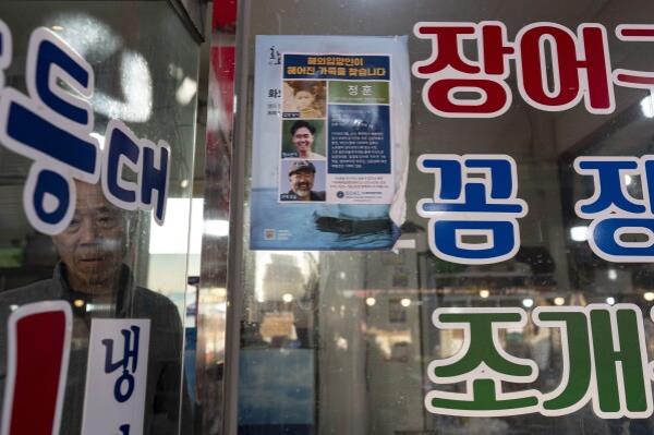 Restaurant owner Shin Byung-chul looks from behind a flyer he put up of Kenneth Barthel, who was abando<em></em>ned in the area as a child and later adopted to Hawaii at 6 years old, at his restaurant in Busan, South Korea, Friday, May 17, 2024. Barthel has visited Korea four times to search for his birth family. (AP Photo/Jae C. Hong)