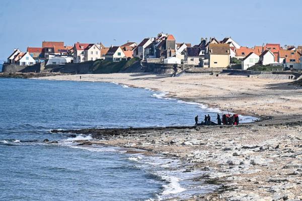 French gendarmes use a tractor to pull a damaged migrants' boat