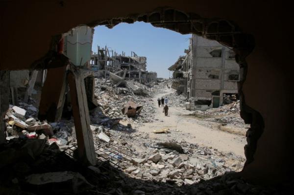 Palestinians walk past the rubble of houses destroyed by the Israeli military.