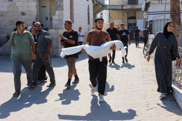 TOPSHOT - A relative carries the shrouded body of ten-year-old Sama al-Debs, who was killed during an Israeli army operation in the Jabalia refugee camp in the central Gaza Strip, ahead of her funeral on October 18, 2024, amid the co<em></em>ntinuing war between Israel and the Palestinian militant group Hamas. (Photo by Omar AL-QATTAA / AFP)