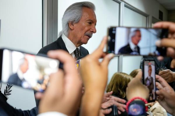 Jose Ruben Zamora leaves court, as people record him on their cellphones.