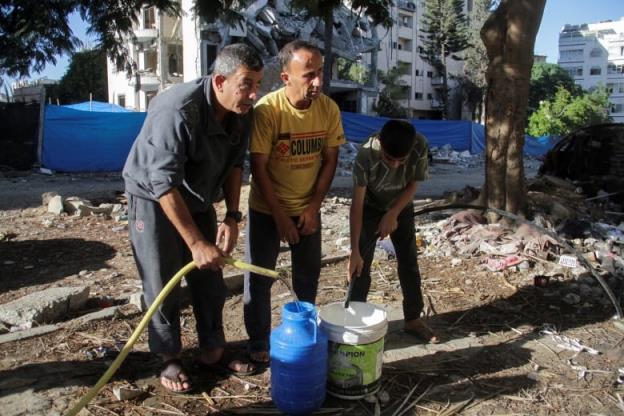 Three men fill water containers.