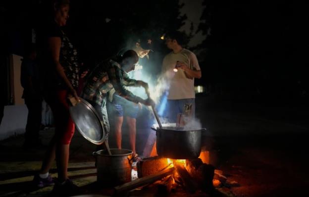 People cook soup over an open fire, at night on a street.