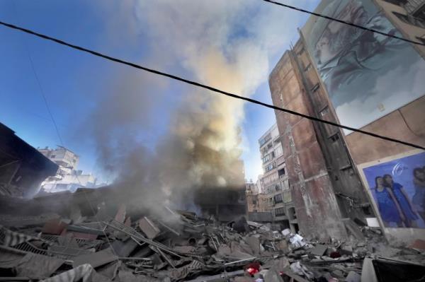 Smoke rises near a giant portrait of the late Hezbollah military commander Imad Mughniyeh from a destroyed building that was hit by an Israeli airstrike in Dahiyeh, a southern suburb of Beirut, Lebanon, Sunday, Oct. 20, 2024. (AP Photo/Hussein Malla)