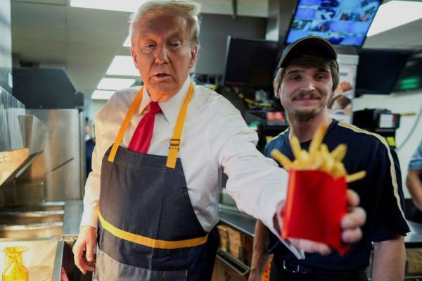 Do<em></em>nald Trump hands fries to someone during a campaign stop at a McDonald's