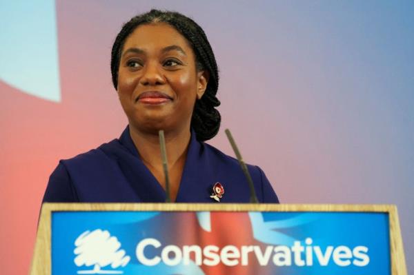 Kemi Badenoch smiles as she stands at a podium with the Co<em></em>nservative Party logo on it