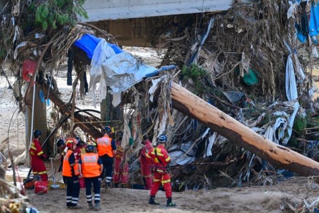 Rescuers stand near flood debris.