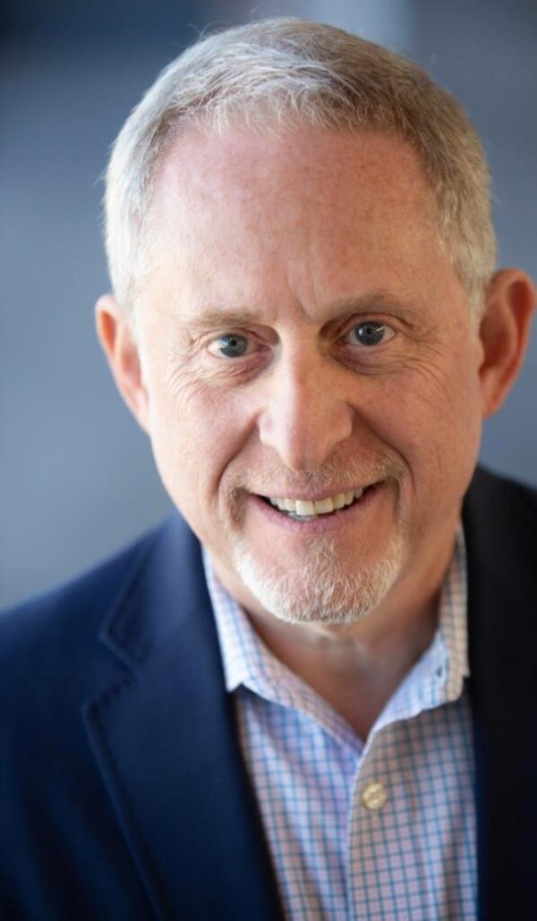 Fermi paradox: A headshot of a white middle aged man in a suit without a tie, smiling.