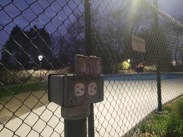 An outdoor electrical outlet in a parking lot.