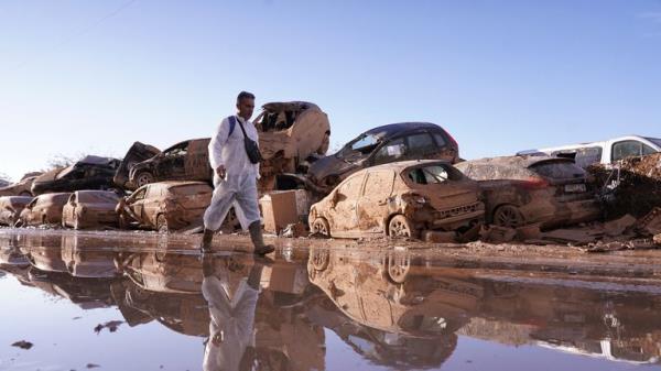 A man walks past stacked up cars after floods in Catarroja.
Pic: AP