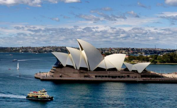 The Sydney Opera House and boats going by.