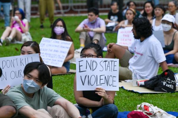 Attendees hold signs during a protest against the death penalty at Speakers' Corner in Singapore on April 3, 2022. (Photo by Roslan RAHMAN / AFP)