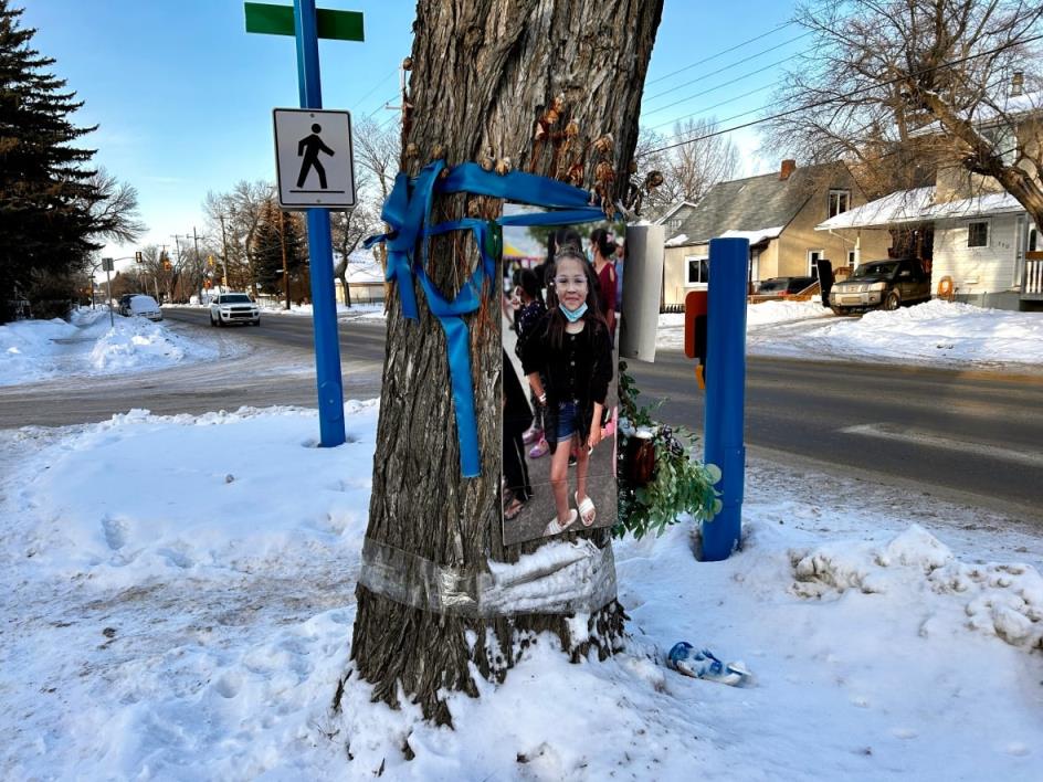 A picture of a young girl tied to a tree with ribbons.