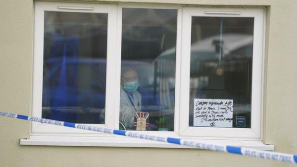 A forensic investigator is seen inside property in Redditch with a tribute in the window. Pic: PA