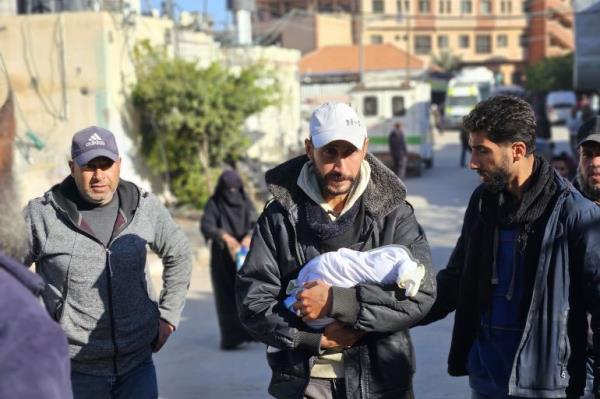 Mahmoud al-Faseeh carries the body of his daughter, three-week-old Sila, who froze to death in the family tent in al-Mawasi