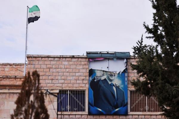 A torn poster of Syria's ousted President Bashar al-Assad hangs on a building