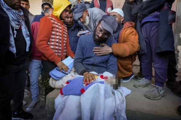 Yahya al-Batran grieves as he holds the body of his 20-day-old son Jumaa, who died from hypothermia, at Al-Aqsa Martyrs Hospital in central Gaza