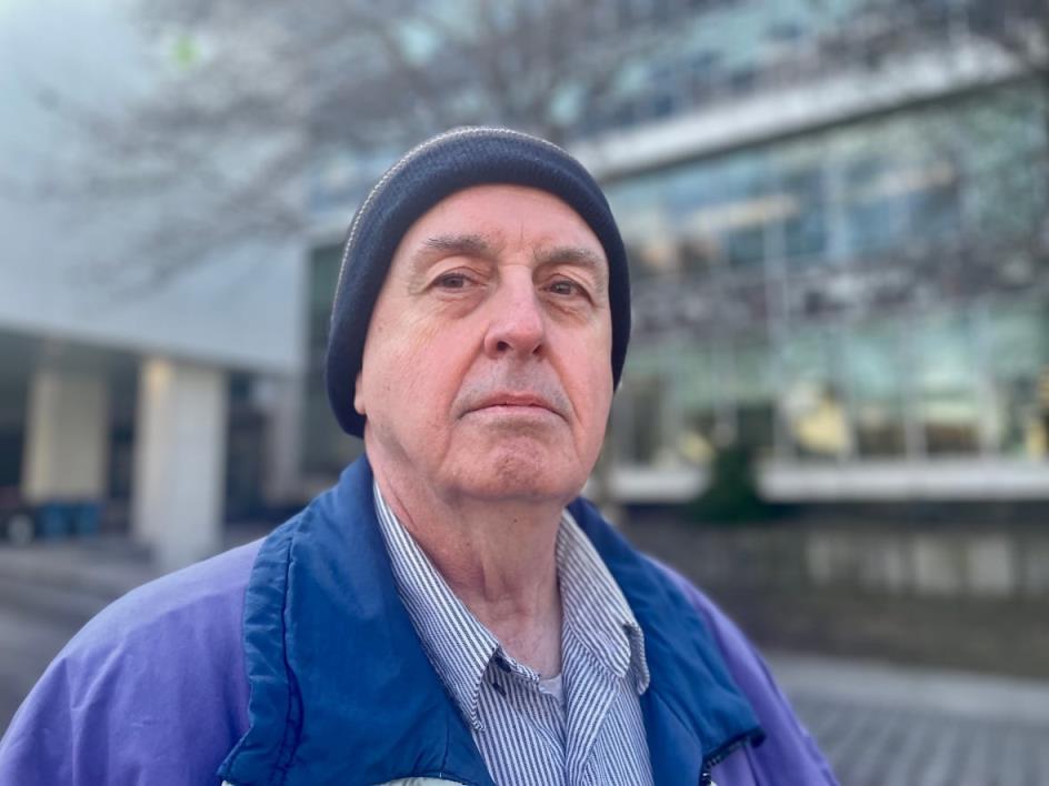 A man in a blue coat in front of city hall.