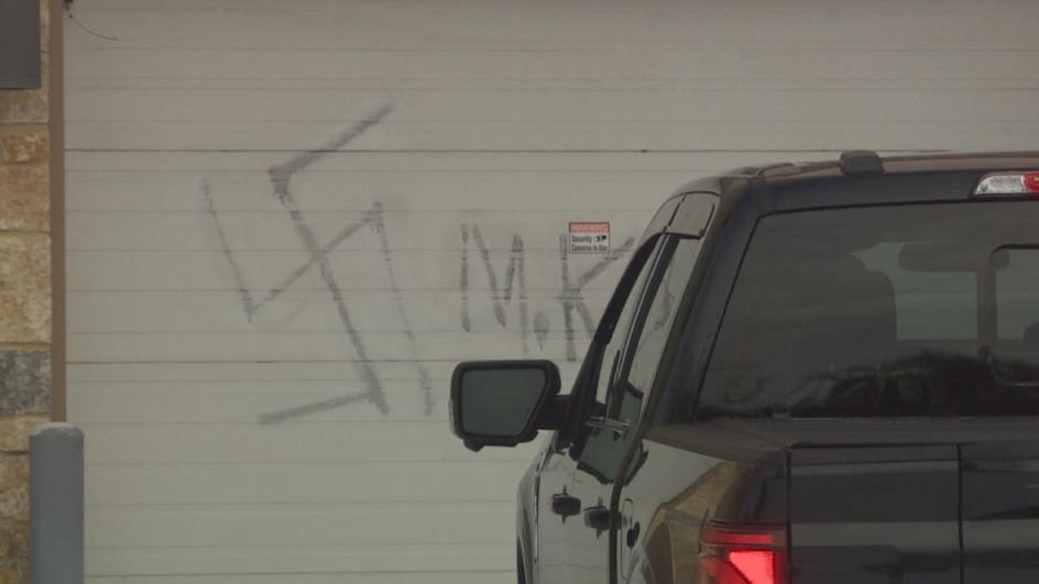 The graffiti of a swastika is sprayed painted in the parking lot door of a co<em></em>ndo building.