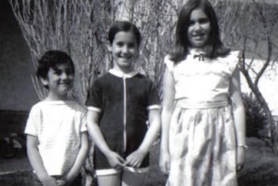 A black-and-white photo showing a boy and two older girls.