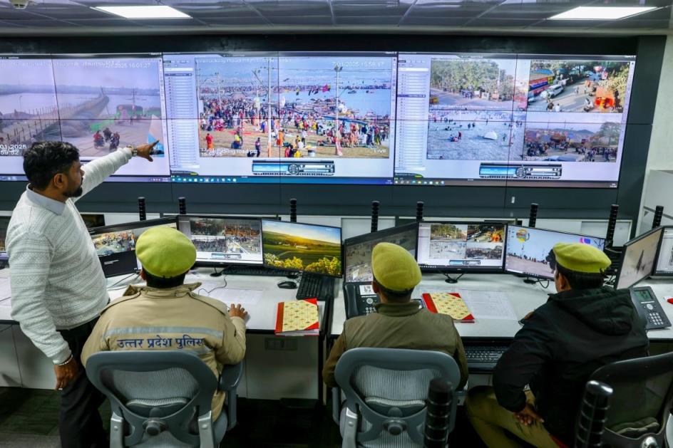 People sitting at desks looks at crowds on monitors.