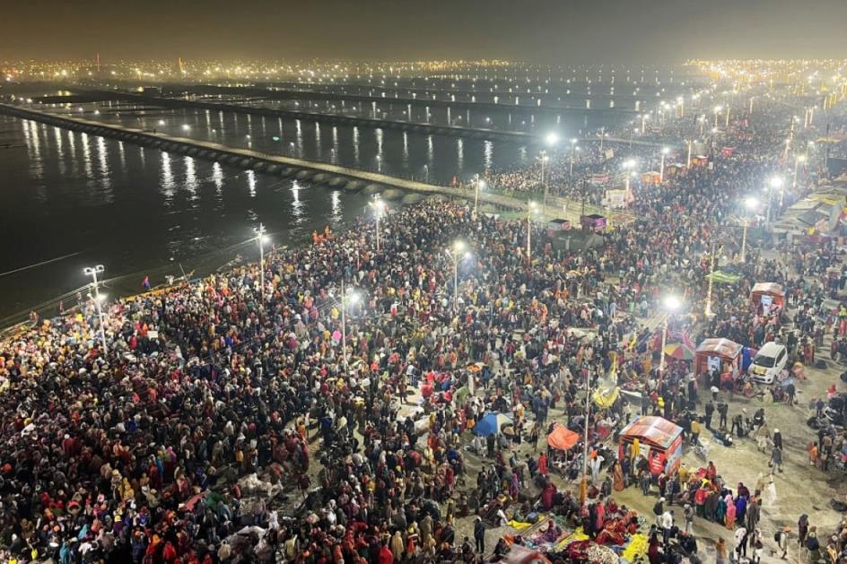 An nighttime aerial view of a massive crowd along a wide river that has numerous bridges crossing it.